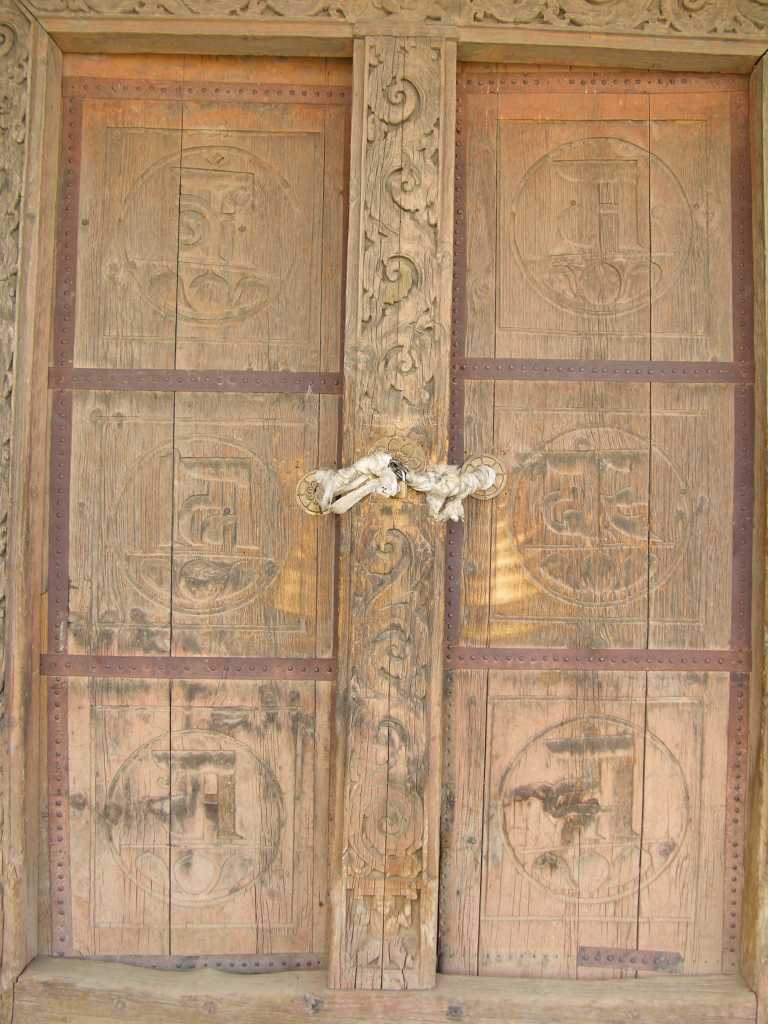 Tibet Guge 07 Tsaparang Red Temple 02 Door The original chapel door is made of deodar cedar with concentric frames and carvings of Shakyamuni in meditation, bodhisattvas, mantras and elephants. Each door has three circular medallions inscribed with Om Mani Padme Hum, unique in Tibet.